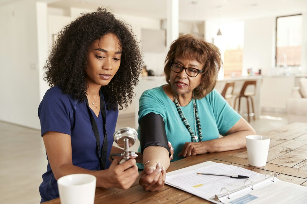 Female healthcare worker checking the blood pressure of a senior woman during a home visit