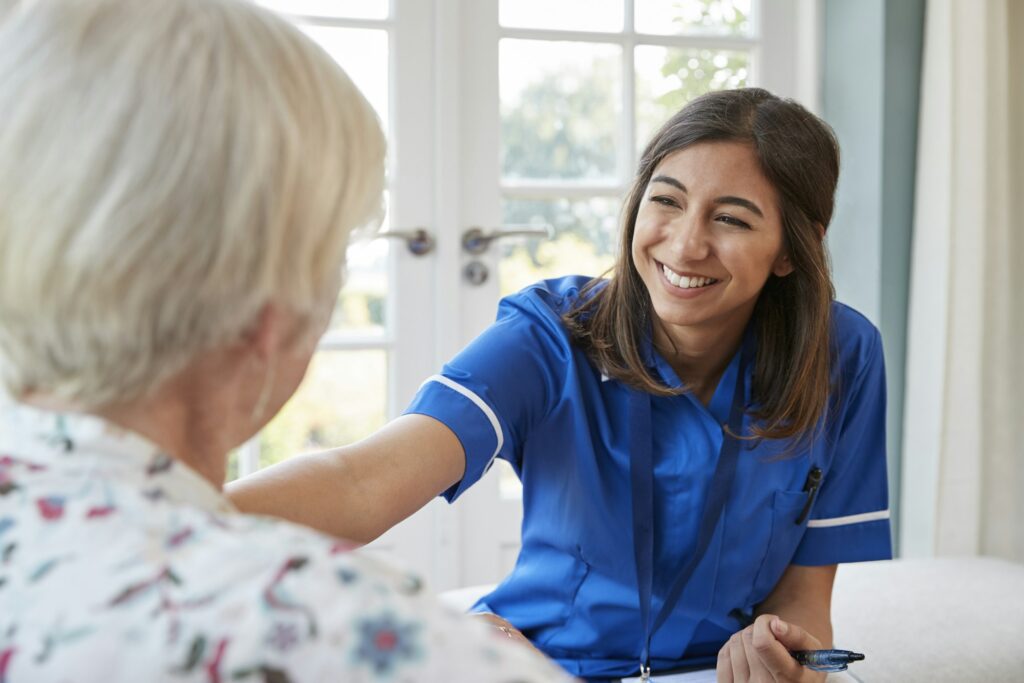 Young care nurse on home visit comforting senior woman